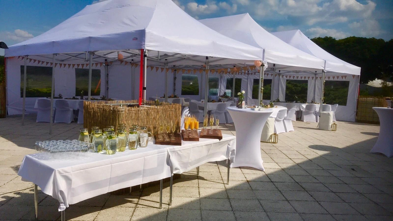 Terrasse mit weißen Pavillons, gedeckten Tischen und Getränkebuffet